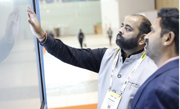 Delegates seated at COLTEC booth viewing panel demonstration
