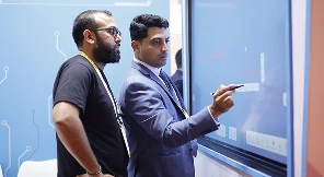 Educators interacting with COLTEC team member beside panel screen
